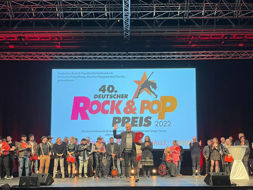 Verleihung auf der großen Bühne beim Deutschen Rock & Pop Preis 2022 – Alfred Bischof mit seiner Auszeichnung, umgeben von Musik, Licht und einem Moment voller Emotionen. Verleihung auf der großen Bühne beim Deutschen Rock & Pop Preis 2022 – Alfred Bischof mit seiner Auszeichnung, umgeben von Musik, Licht und einem Moment voller Emotionen.