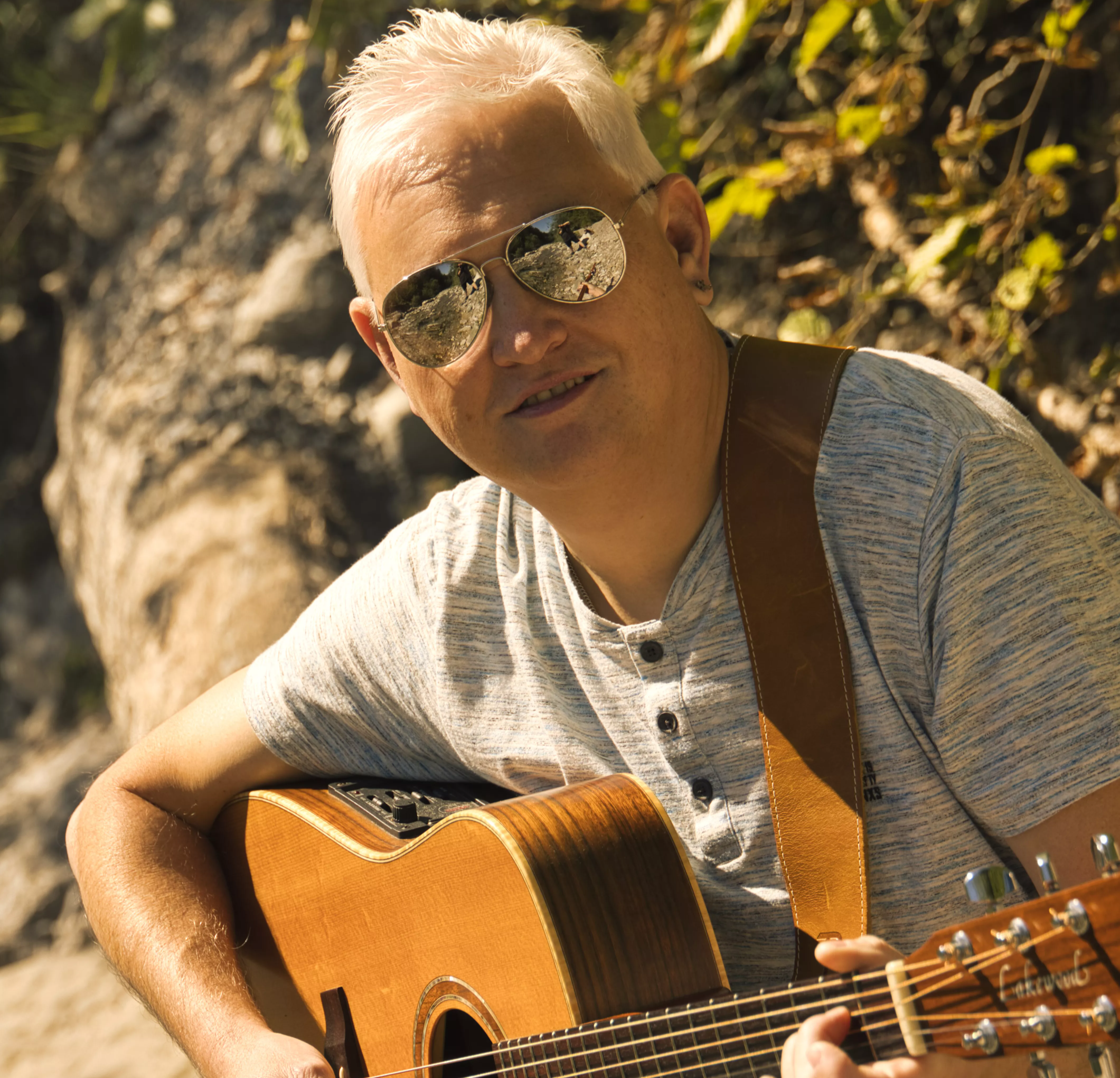 „Alfred Bischof mit Gitarre und Sonnenbrille in der Natur beim Musizieren“